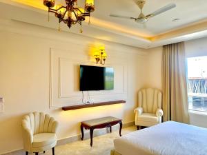 a bedroom with a bed and two chairs and a tv at The Arte in Rohtak