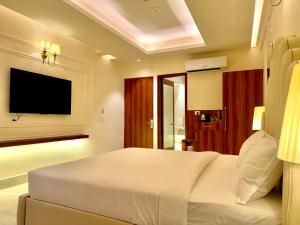 a bedroom with a white bed and a flat screen tv at The Arte in Rohtak +31 photos