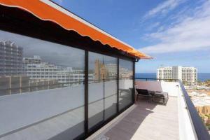 a balcony with a view of the ocean and buildings at Eden Rentals Olympia Sunny Seaviews in Playa de las Americas