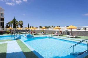 a large swimming pool with yellow umbrellas and chairs at Eden Rentals Olympia Sunny Seaviews in Playa de las Americas