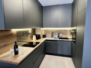 a kitchen with gray cabinets and two wine glasses at Slatine Residence Apartament No 1 in Slatine