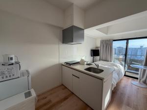 a white kitchen with a sink and a bed at KOTI Hakata in Fukuoka
