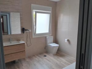 a bathroom with a toilet and a sink and a window at Casa Camiño dos Faros in Sinde