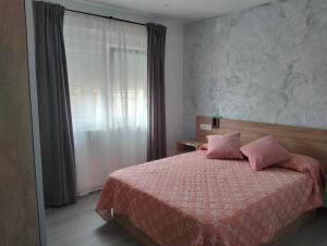 a bedroom with a bed with pink pillows and a window at Casa Camiño dos Faros in Sinde