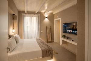 a bedroom with a white bed and a tv at Palermo Inn Boutique Hotel in Palermo