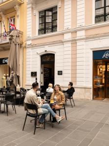 a group of people sitting at tables outside a building at Sparano Palace - Luxury Maison in Bari