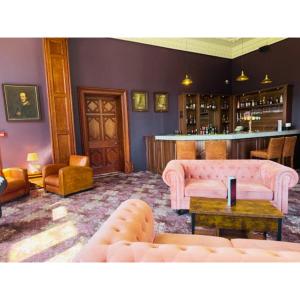 ein Wohnzimmer mit einem rosa Sofa und einer Bar in der Unterkunft Wroxall Abbey Hotel & Estate in Wroxall