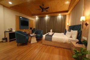a hotel room with a bed and chairs and a television at DN Resort Dharamshala in McLeod Ganj