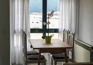 a dining room table and chairs with a window at Apartamentos Salceda in Noja