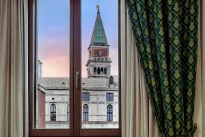 a window with a view of a building with a clock tower at Hotel Commercio & Pellegrino in Venice