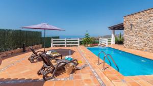 a swimming pool with two chairs and an umbrella at Villa Infinity Torrox by Ruralidays in Torrox