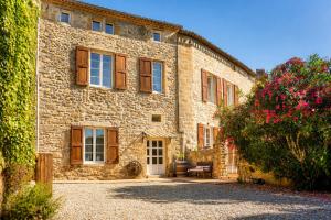 a large stone building with wooden windows and flowers at Domaine du Prieuré avec Piscine Ancien Couvent & Presbytère in Carcassonne