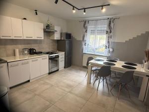 a kitchen with white cabinets and a table with chairs at APARTAMENTY CIUKAJ in Paczków