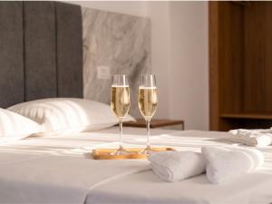 two champagne glasses on a tray on a bed at Hotel Four Islands in Ksamil