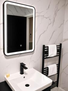 a bathroom with a white sink and a mirror at Beyond Hotel & Apartments in Burnley +1 photo