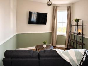 a living room with a couch and a tv on the wall at Beyond Hotel & Apartments in Burnley