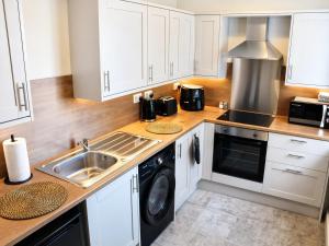 a kitchen with white cabinets and a sink at Beyond Hotel & Apartments in Burnley