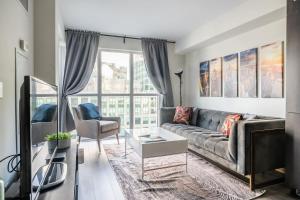 a living room with a couch and a table at Stylish 1BR plus Den Suite with Parking, Sleeps 4) in Toronto