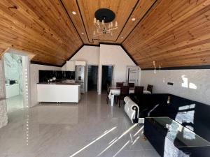 a living room with a wooden ceiling and a kitchen at Firepalace Gabala in Gabala