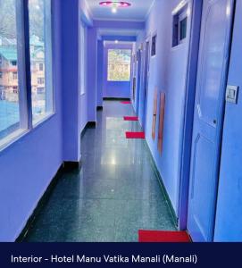 a hallway in a building with blue walls and ailed floor at Hotel Royal Selection in Manāli