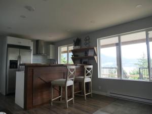 a kitchen with a bar with two chairs and windows at Howe Sound View in Bowen Island