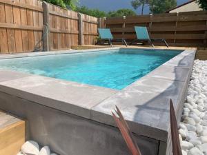 a swimming pool with two chairs in a backyard at Villa des Ponteils in Moliets-et-Maa