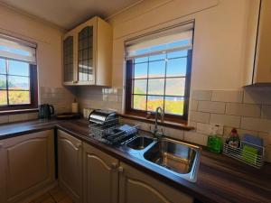 a kitchen with a sink and two windows at Braehead Cottage in Glencoe +27 photos