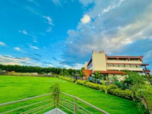 a building with a green field in front of a building at Hotel Ashoka Resort in Ellora