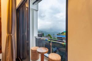 a balcony with two stools and a window with a view at Accom Hotel in Ilām