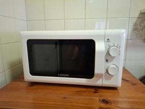 a white microwave sitting on top of a wooden table at Anne's Cottage in Durban