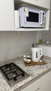 a kitchen counter with a microwave and a stove top at Departamento en Chivilcoy in Chivilcoy