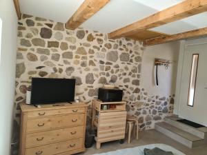 a living room with a tv and a stone wall at Au petit nid in Vilars