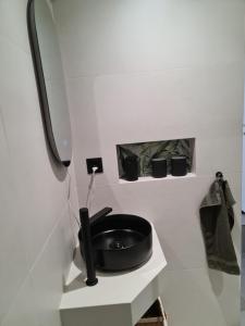 a bathroom with a black sink on a shelf at Au petit nid in Vilars