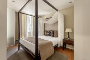 a bedroom with a canopy bed and a window at Casas do Porto - Ribeira Apartments in Porto