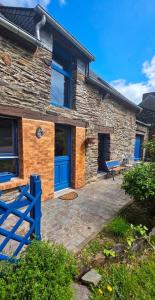 a stone house with a blue fence in front of it at Penty horizon de Brocéliande in Augan