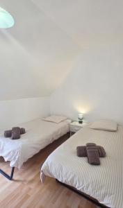 two beds in a room with white walls and wooden floors at Penty horizon de Brocéliande in Augan