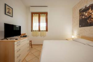 a bedroom with a bed and a flat screen tv at Appartamenti La Vecchia Posta - 50 mt dal Mare in Marina di Grosseto
