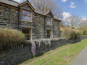 an old stone house with a stone wall at Ysgoldy in Dolwyddelan
