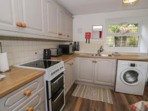 a kitchen with white cabinets and a washing machine at Ysgoldy in Dolwyddelan