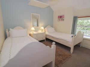a white bedroom with two beds and a window at Ysgoldy in Dolwyddelan