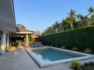 a swimming pool in a yard next to a house at Maprao Villa in Mae Nam