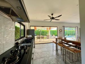 a kitchen with a stove and a dining room with a table at Maprao Villa in Mae Nam