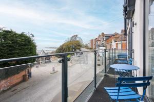 a balcony with blue tables and chairs on a street at Host & Stay - 2a Hamilton Road in Felixstowe