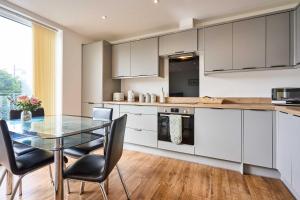 a kitchen with white cabinets and a glass table at Host & Stay - 2a Hamilton Road in Felixstowe