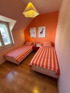 two beds in a room with orange walls at Résidences Les Murots 1 in Saint-André-les-Vergers