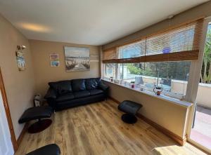 a living room with a black couch and a window at 2 Bedroom - Seaside Apartment in Dawlish Warren