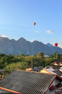 a hot air balloon flying over the roofs of houses at Camellia Hotel in Vang Vieng