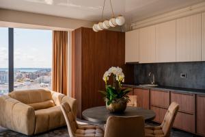 a living room with a table and a couch and a kitchen at Noble Hotel by Building Stefan in Mamaia Sat/Năvodari +33 photos