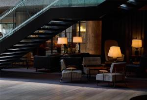 a lobby with chairs and tables and a staircase at The Edwardian Manchester, A Radisson Collection Hotel in Manchester