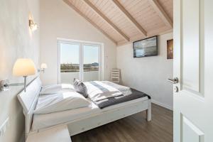 a white bedroom with a bed and a window at Ferienhaus Kampfläufer in Dagebüll